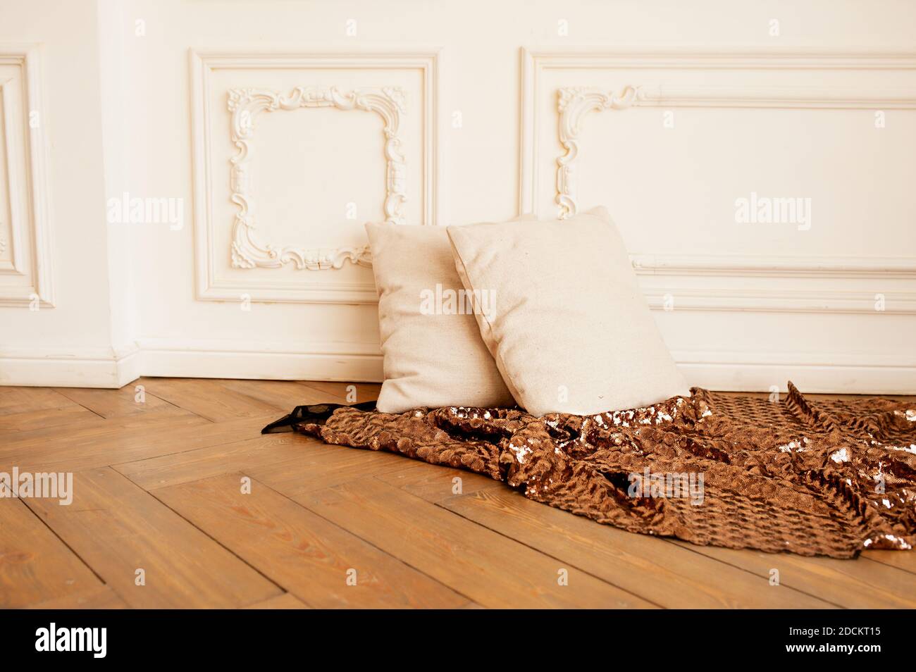 deux oreillers doux et confortables beige sur le parquet avec une couverture en bronze brillant et un stuc blanc sur le mur. minimalisme à l'intérieur, Banque D'Images