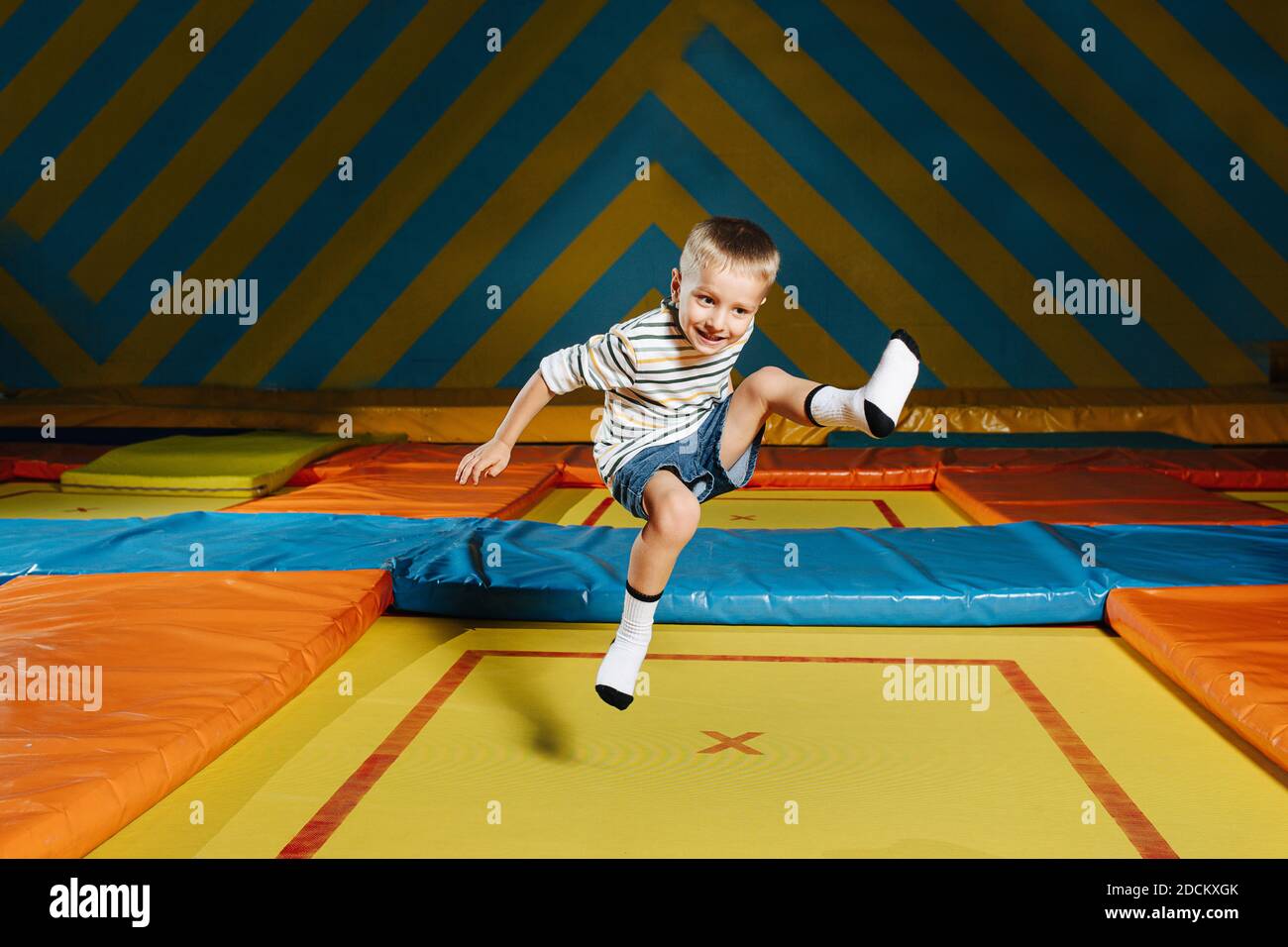 Un garçon enthousiaste sautant sur un trampoline carré dans le centre de  divertissement Photo Stock - Alamy