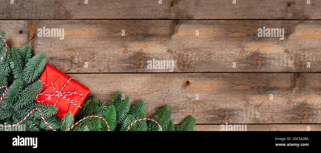 Brindilles de sapin de Noël et cadeau à rayures rouges ruban sur fond en bois avec espace de copie pour le texte Banque D'Images