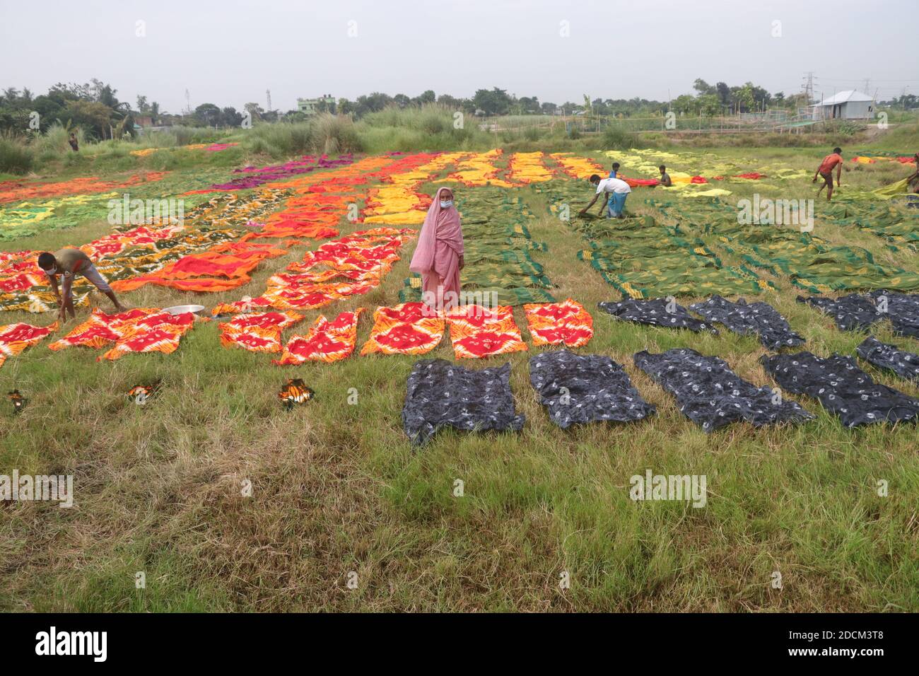 Les travailleurs bangladais collectent des tissus après les avoir séchés sous le soleil dans une usine de teinture à Narayanganj, au Bangladesh. Nazmul Islam/Alamy stock photo Banque D'Images
