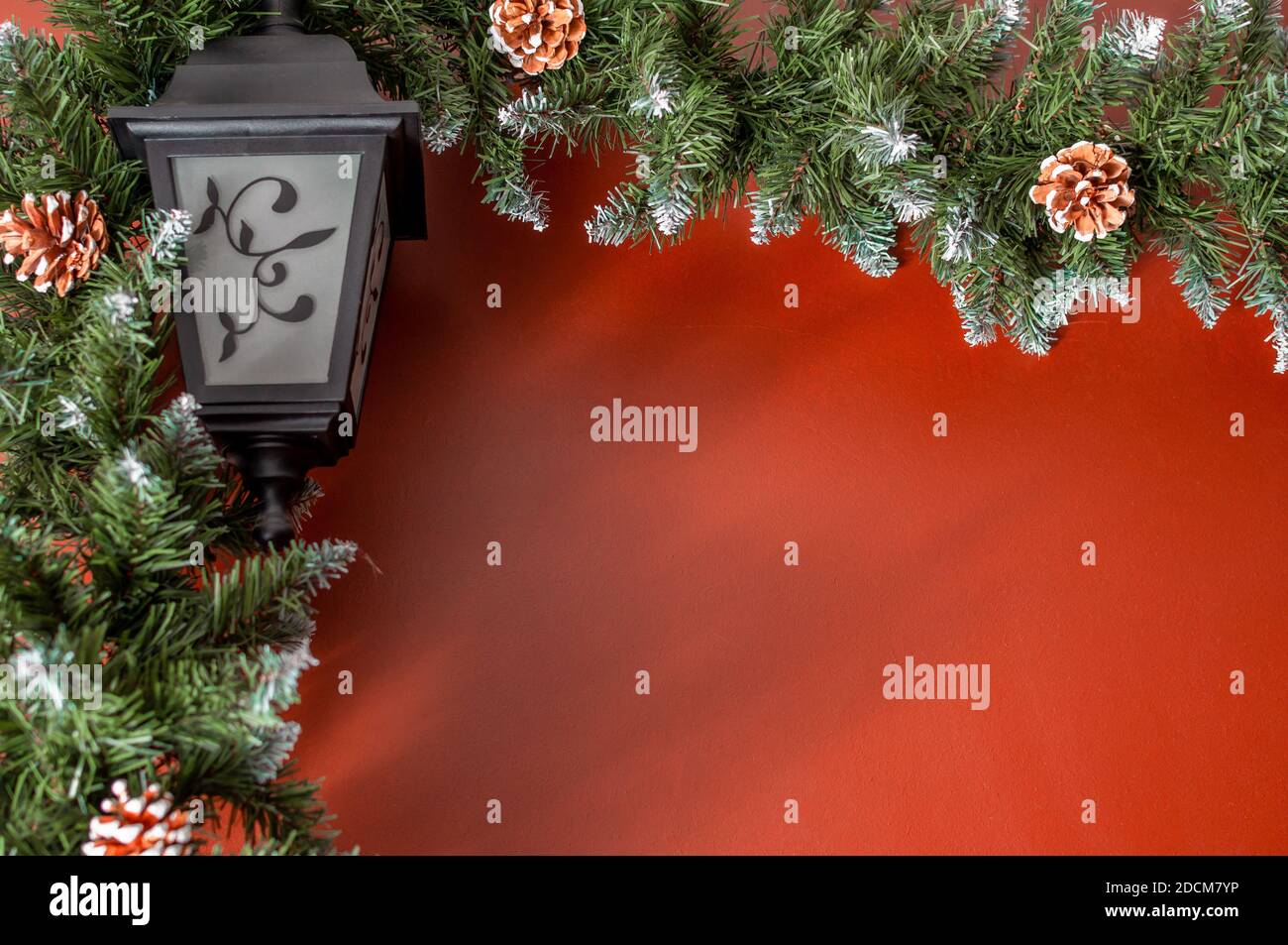 Guirlande De Noel Avec Branches De Sapin Vert Et Cones Sur Le Fond D Un Mur Rouge Avec Espace Pour Le Texte Faible Profondeur De Champ Et Mise Au Point Selective Photo Stock