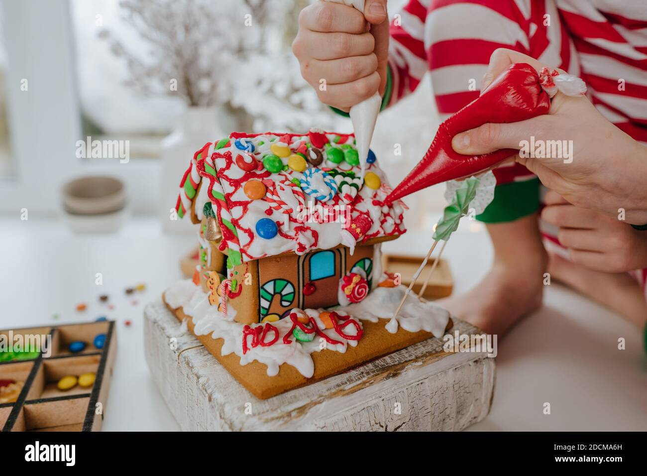 Gros plan des enfants décoré maison de pain d'épice de Noël avec glaçant coloré et bonbons sur la table dans la cuisine. Attention sélective sur le hous Banque D'Images