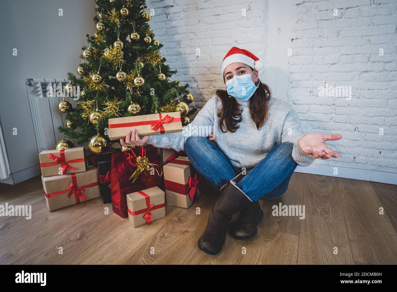 Triste femme avec masque maison seule en auto-isolement à noël sentiment déprimé de deuil et de manque de famille et d'amis. COVID-19 verrouillage et quart Banque D'Images