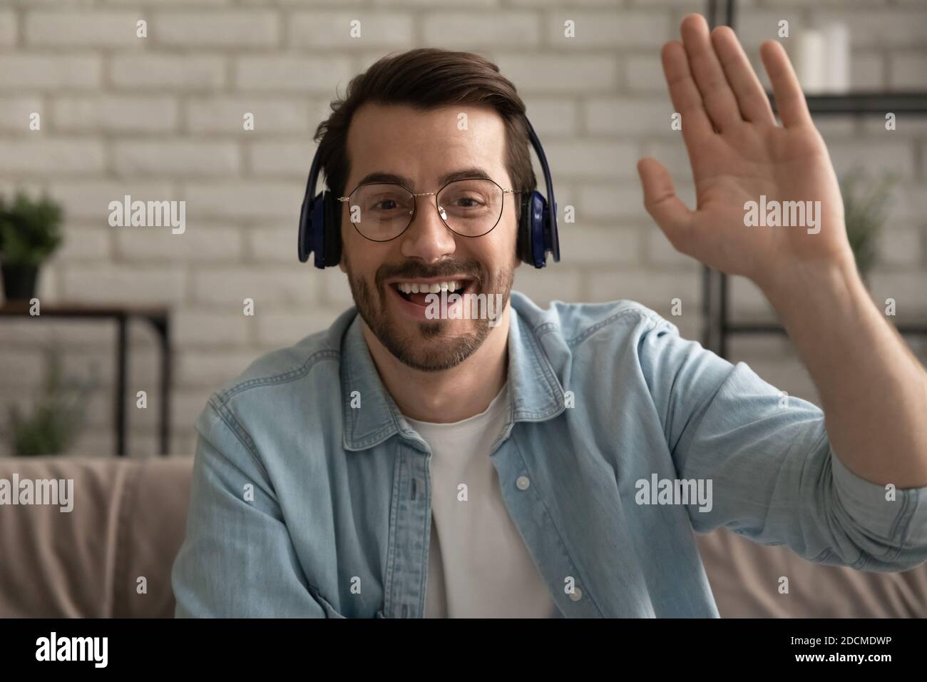 Un jeune homme souriant accueille des amis lors d'une réunion par appel vidéo en ligne. Banque D'Images