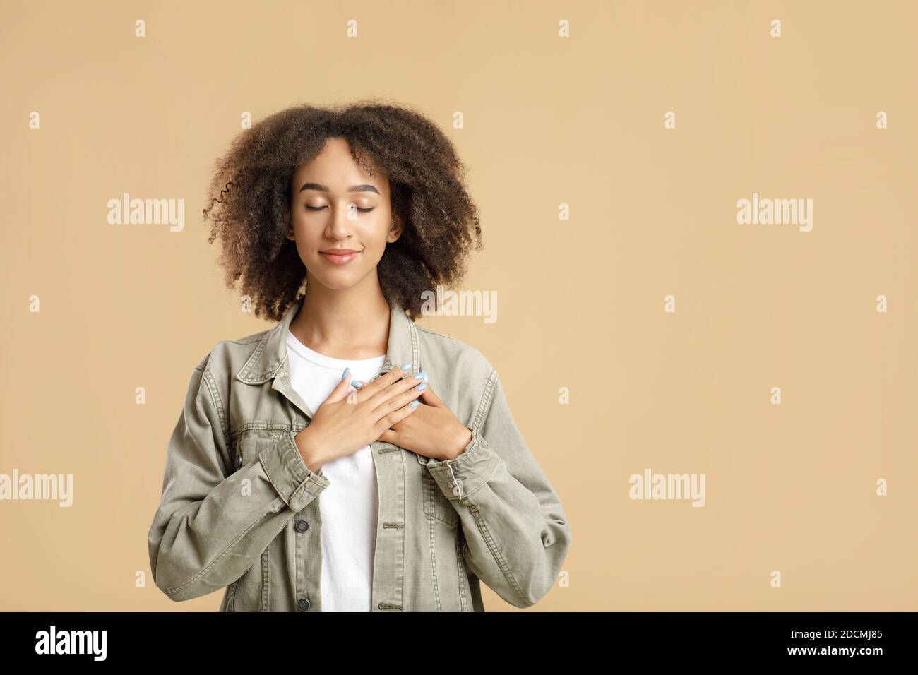 Portrait d'une femme reconnaissante et pleine d'espoir tenant les mains sur la poitrine Banque D'Images