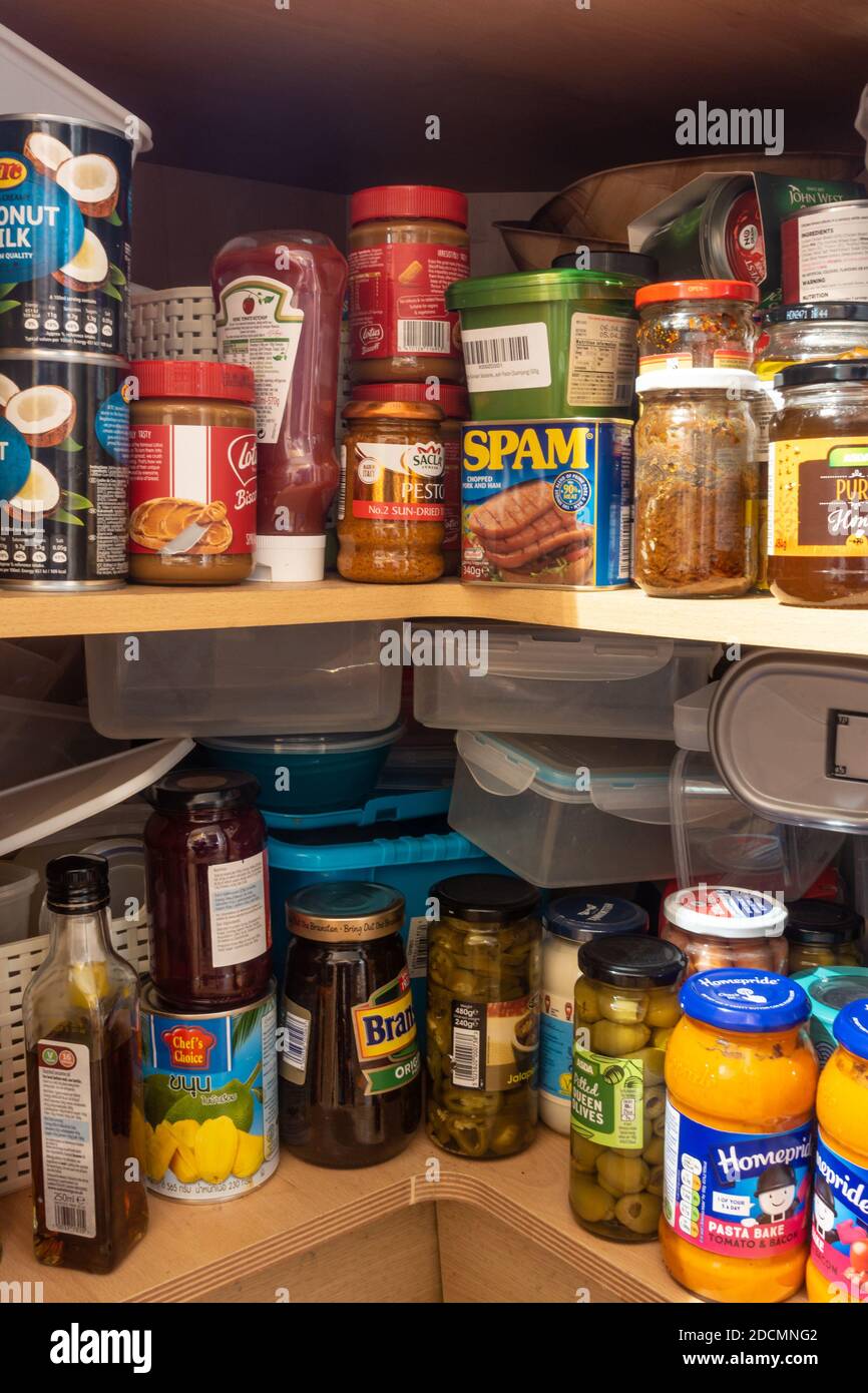 Bouteilles, bocaux et canettes d'aliments stockés dans un placard de cuisine d'angle sous le plan de travail. Banque D'Images