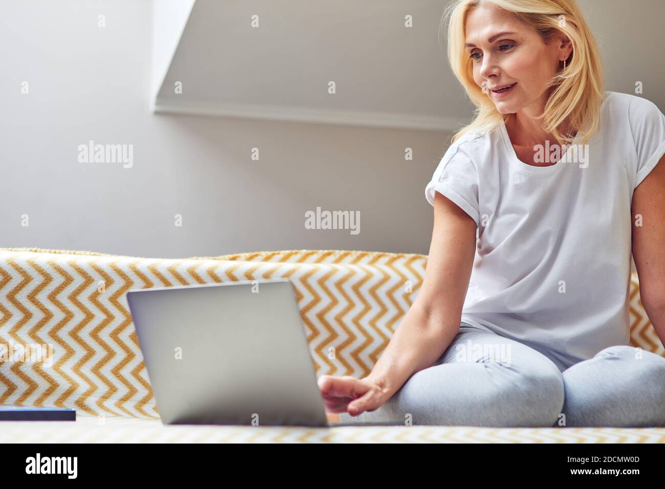 Belle femme de race blanche d'âge moyen travaillant sur un ordinateur portable assis sur un canapé et regardant à l'écran. Concept de travail à domicile Banque D'Images