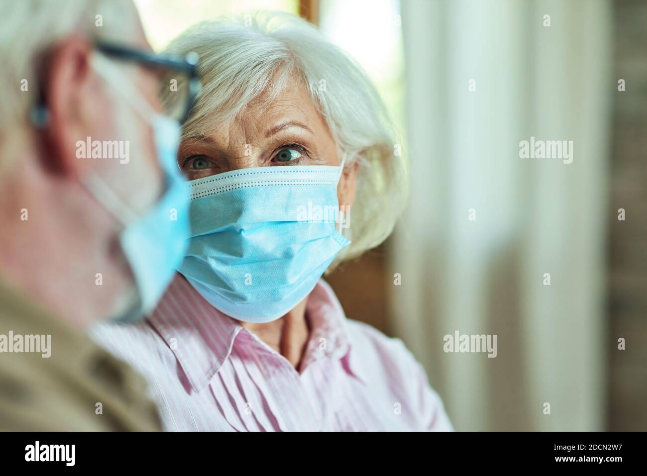 Photo rognée d'une femme âgée regardant son mari tout en portant des masques de protection à la maison. Concept de soins et de santé Banque D'Images