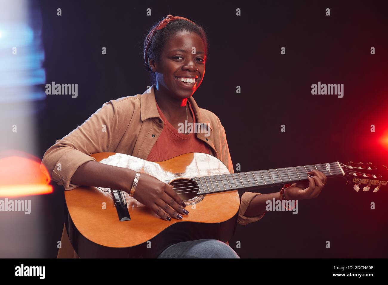 Portrait à la taille de la jeune femme afro-américaine jouant de la guitare  sur scène et souriant, espace de copie Photo Stock - Alamy