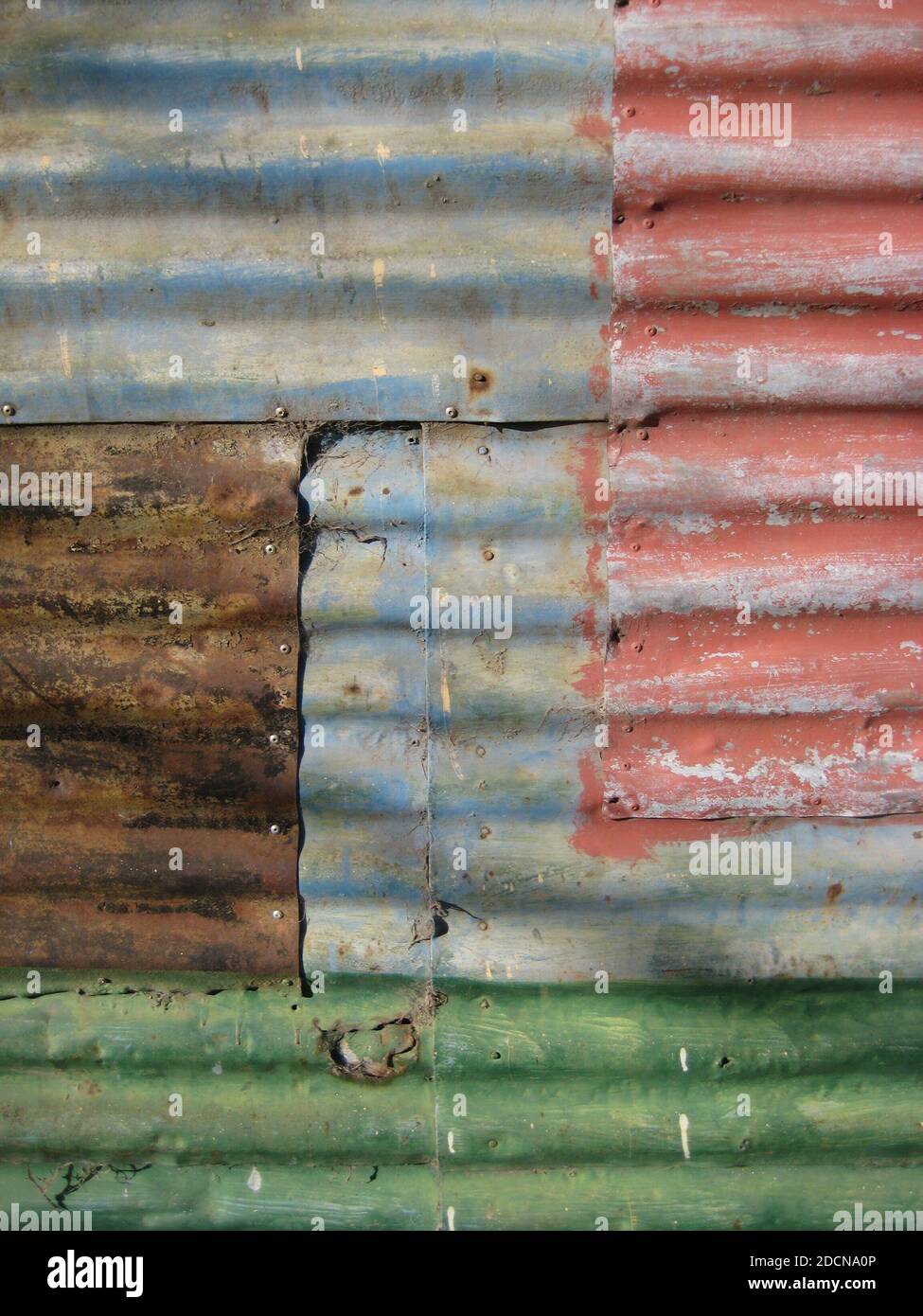 mur fait de feuilles de métal ondulé avec différentes couleurs décolorées et rouille, fond texturé Banque D'Images