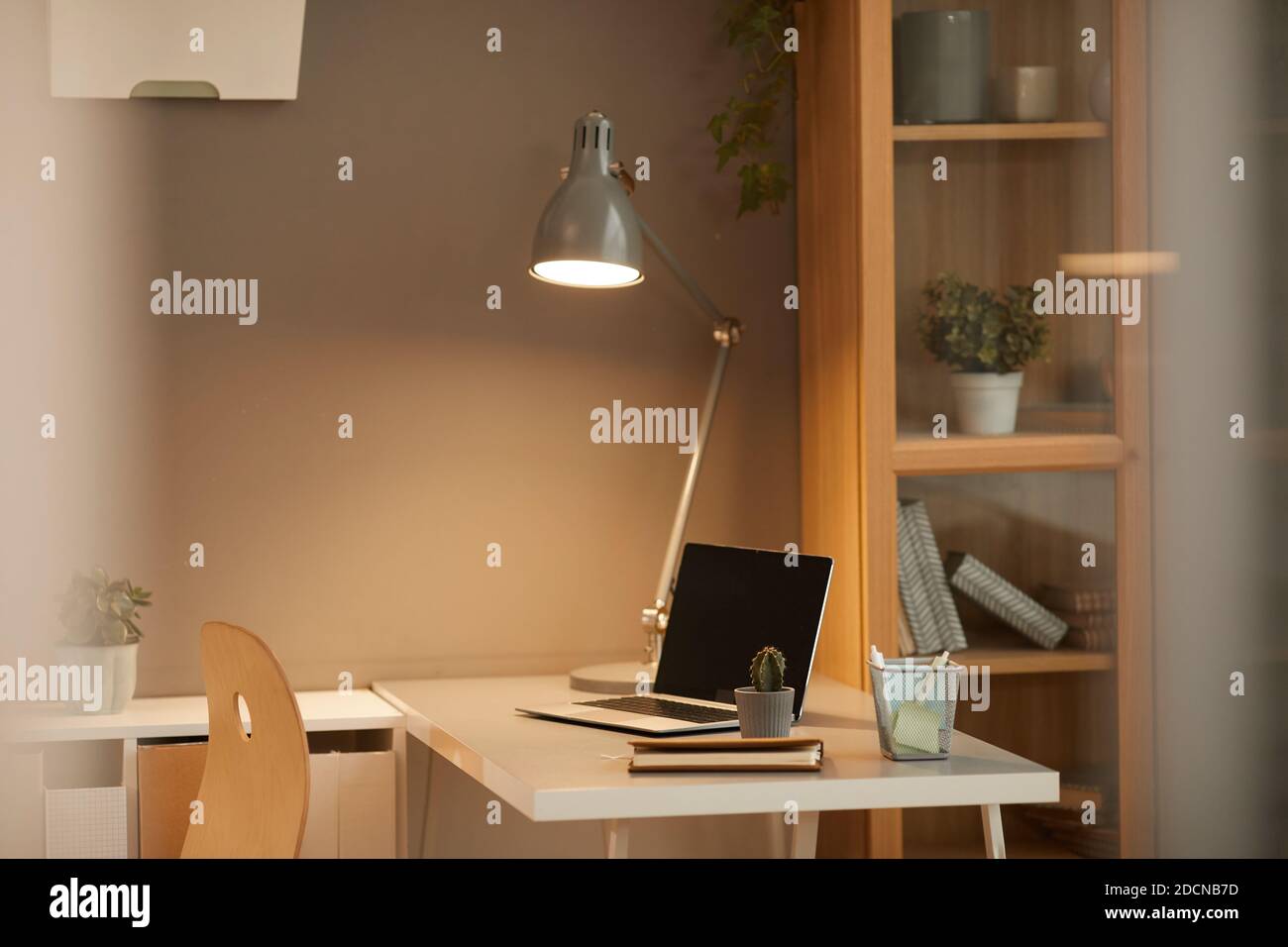 Image d'arrière-plan d'un espace de travail confortable à la maison avec lampe de bureau éclairée dans un design minimal, espace de copie Banque D'Images