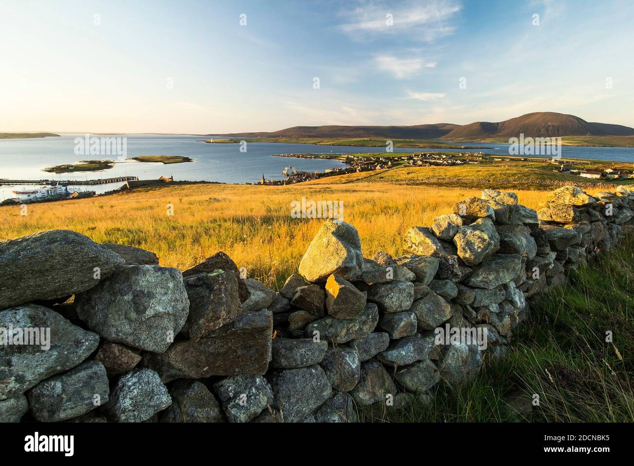 Vue aérienne du lever du soleil au-dessus de Stromness sur les îles Orcades avec mur de pierre sèche au premier plan et îles dans le arrière-plan Banque D'Images