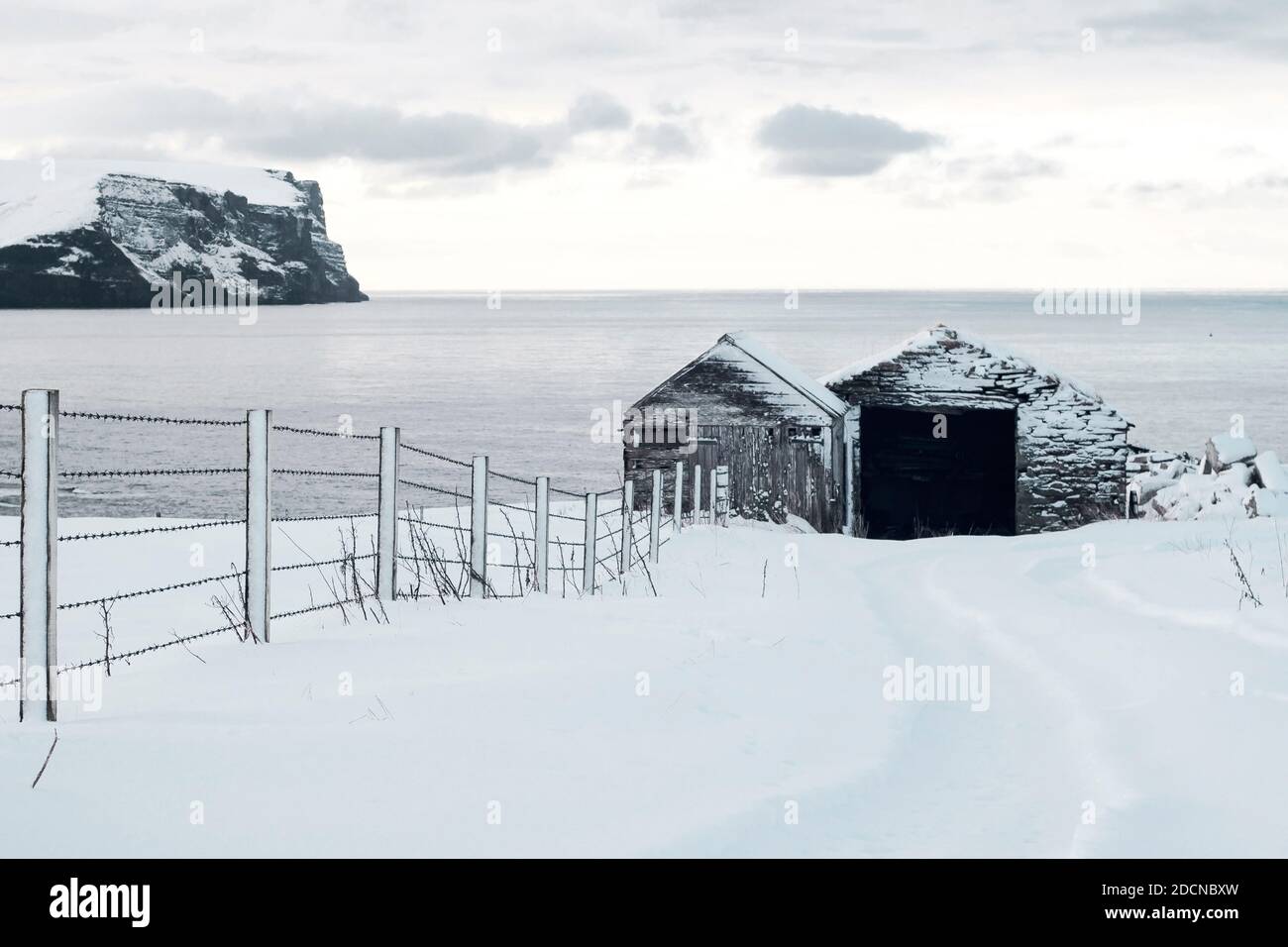 Deux hangars en bois en scène d'hiver avec des falaises dans le Arrière-plan sur les îles Orcades Banque D'Images