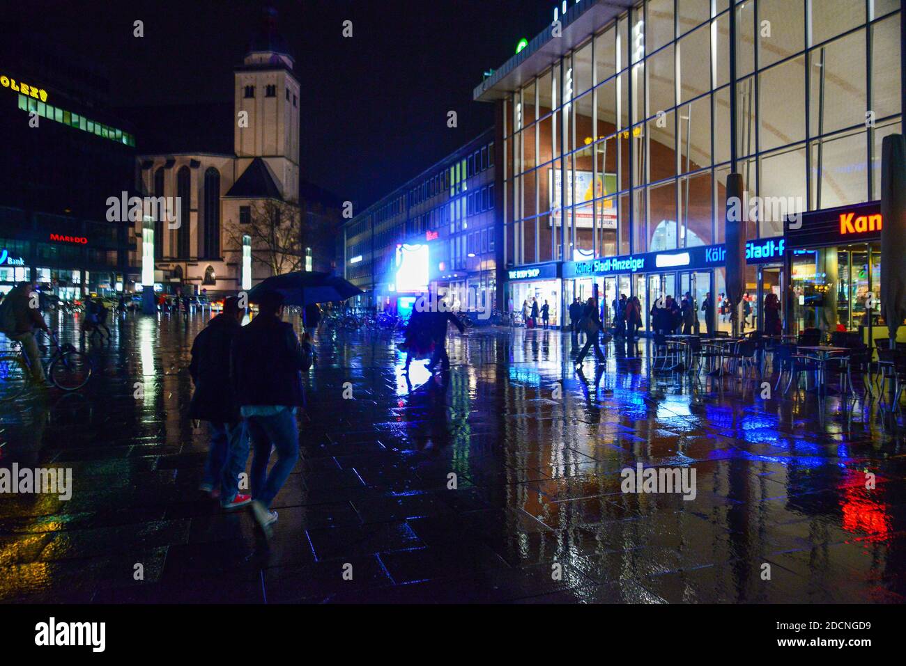 Gare principale à Cologbne et personne non-regnable marchant la nuit. Ccity illuminé . réflexion sur carreaux de béton humide. Banque D'Images