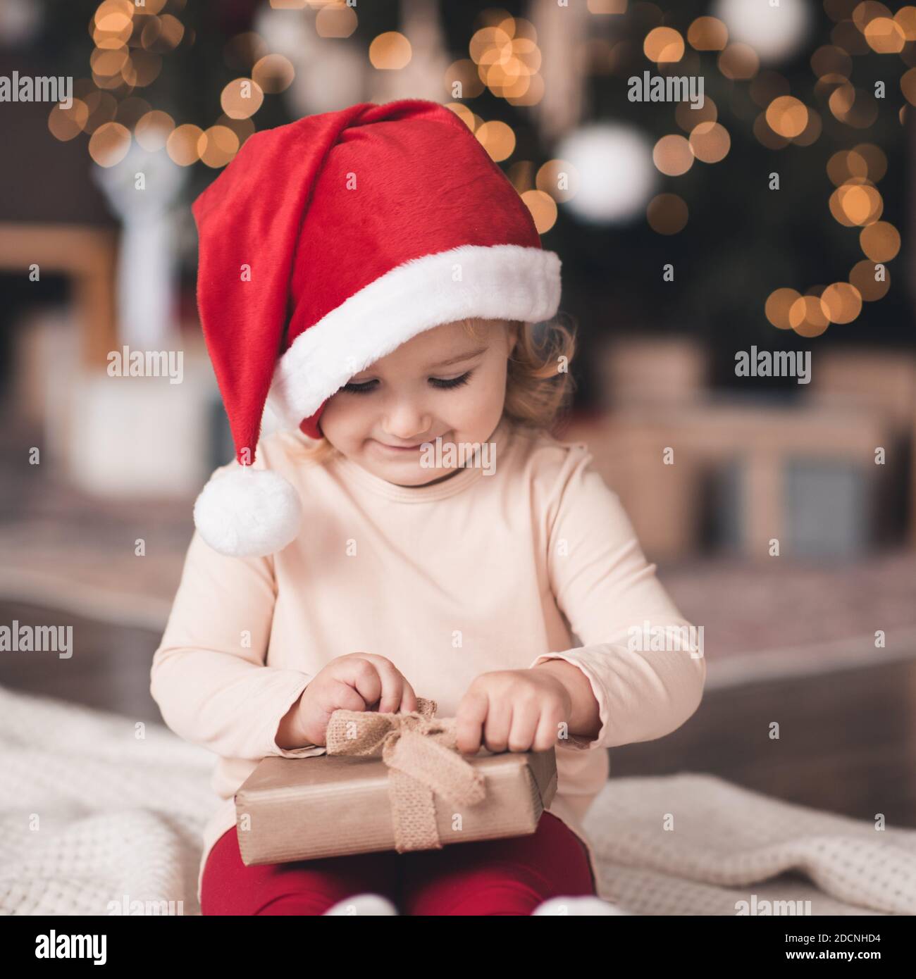 Bébé fille souriante 3-4 ans ouvert Noël boîte cadeau porter chapeau et  pyjama rouge Père noël sur des lumières brillantes gros plan. Saison des  vacances d'hiver Photo Stock - Alamy