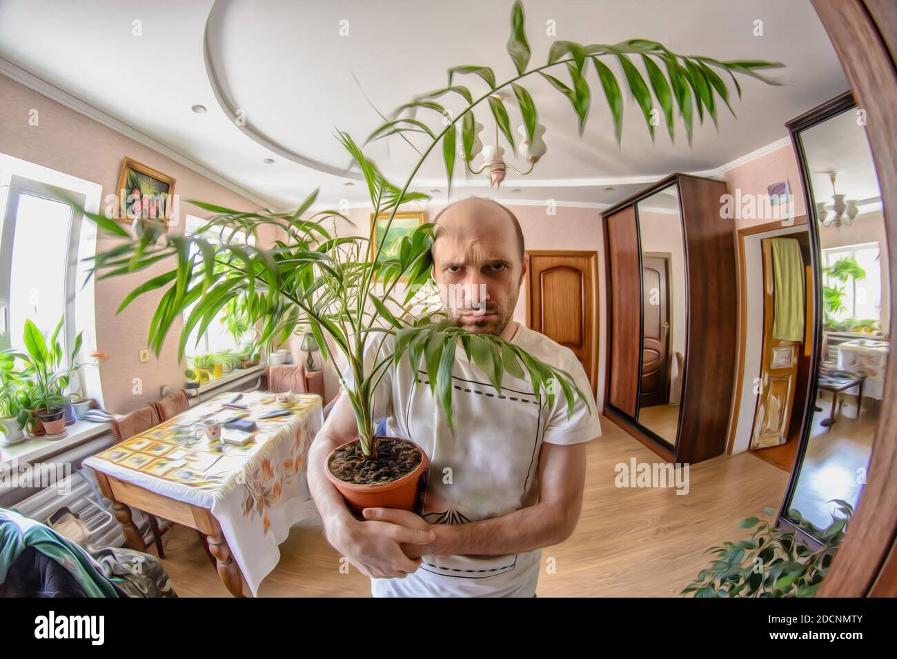 Un homme est debout dans une pièce avec une fleur dans le pot de fleurs. Banque D'Images