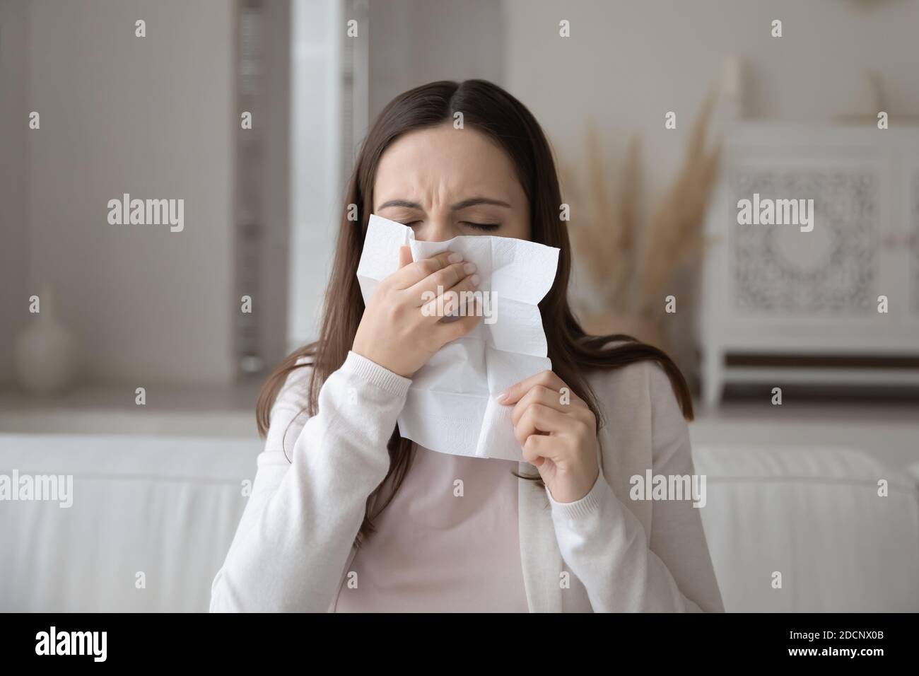 Femme malade du millénaire ayant le nez soufflé froid dans le papier de soie Banque D'Images