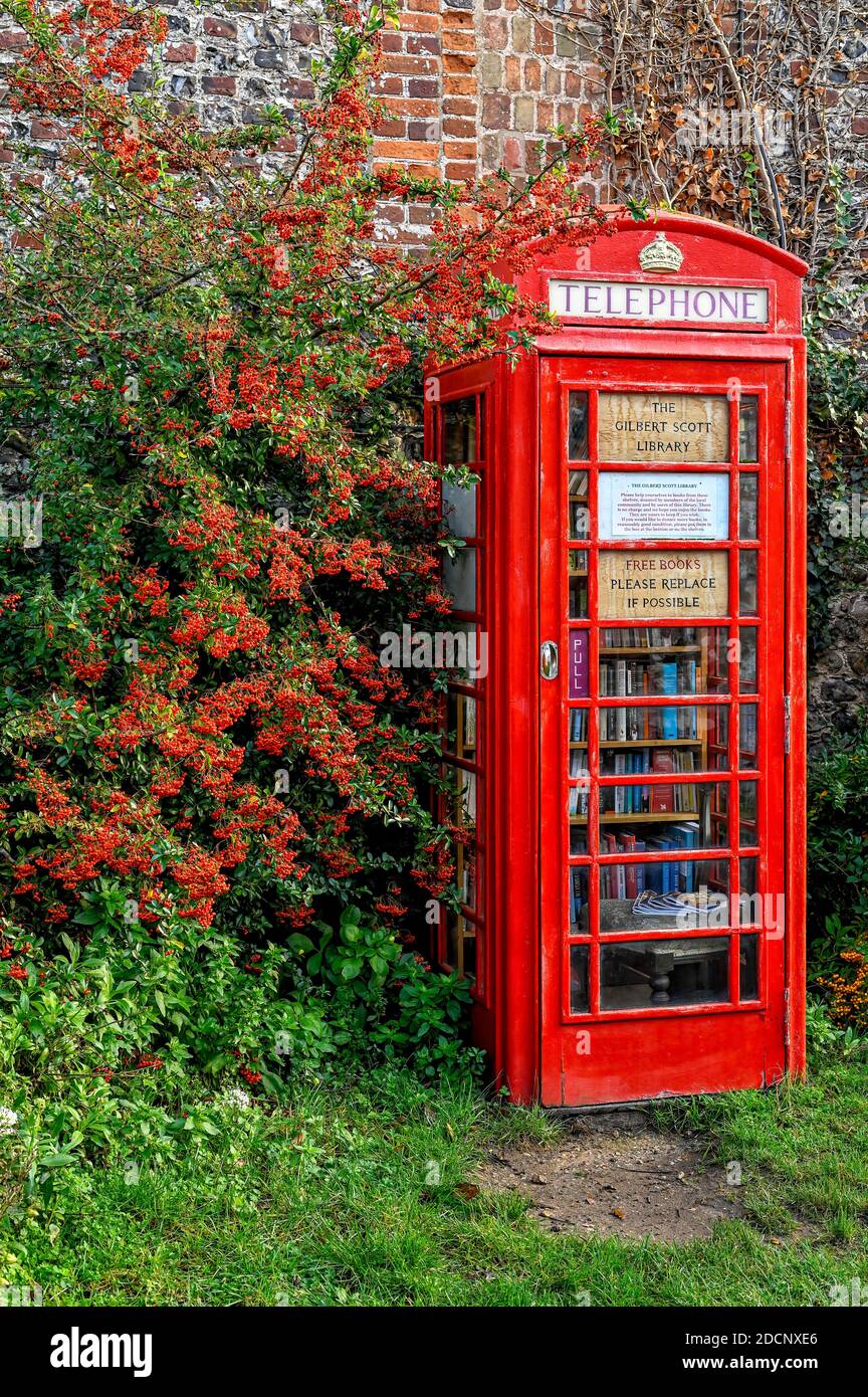 Ancienne boîte téléphonique BT rouge traditionnelle transformée en bibliothèque de prêt dans un village de Norfolk. Banque D'Images