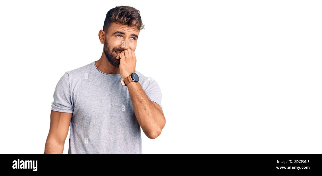 Jeune hispanique portant des vêtements décontractés, aspect stressé et nerveux avec les mains sur la bouche piquant les ongles. Problème d'anxiété. Banque D'Images