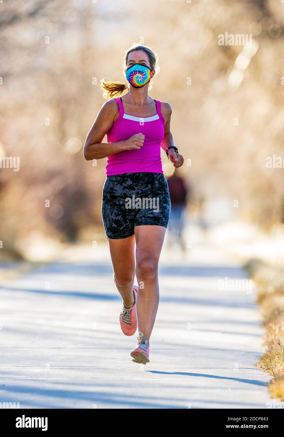 Attrayant; ajusté; femme d'âge moyen portant un masque de protection; courir sur un sentier pavé; Salida; Colorado; États-Unis Banque D'Images
