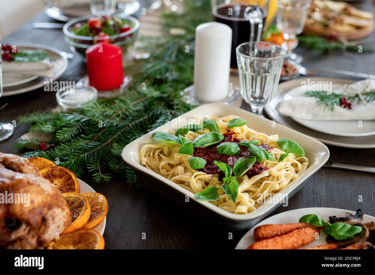 Table festive servie avec des pâtes, de la dinde rôtie, des assiettes, des bougies et d'autres Banque D'Images