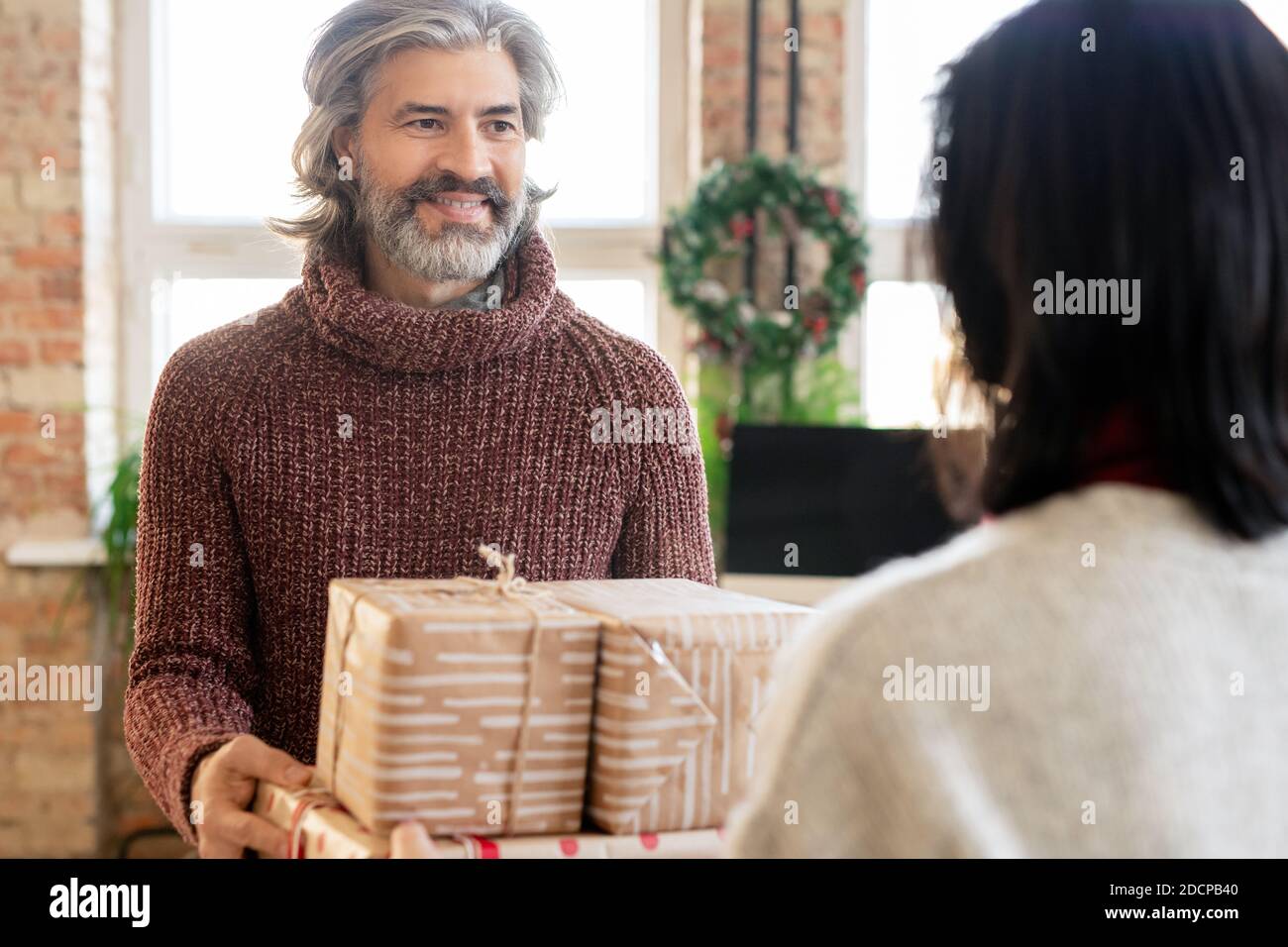 Un homme mûr heureux passant sa femme a emballé des boîtes-cadeaux tout en regardant à elle Banque D'Images