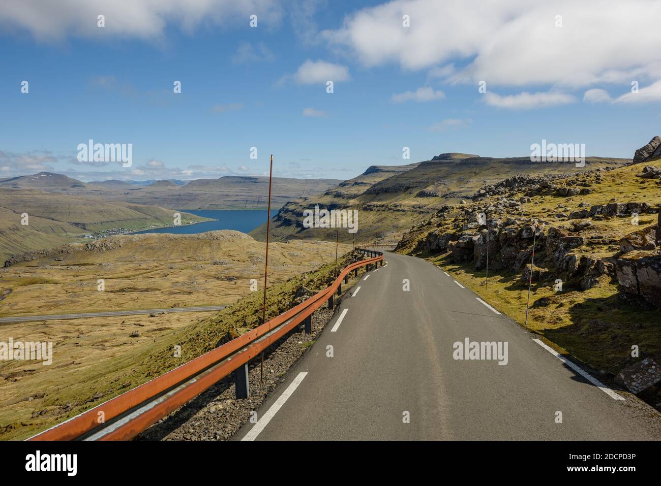 Vue incroyable sur une route vide traversant un terrain rocailleux vert sous le ciel bleu Banque D'Images