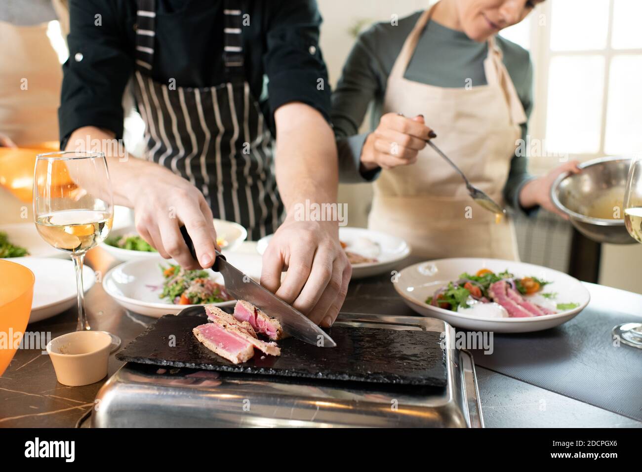 Mains de jeunes hommes entraîneur de cuisine hacher morceau de fumé bœuf à la table Banque D'Images