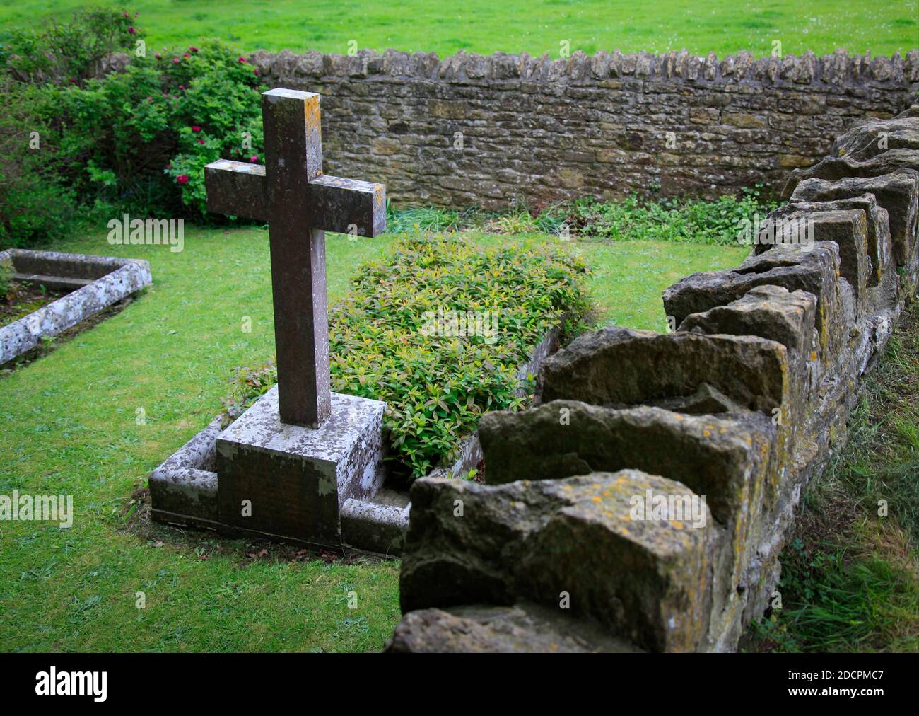 Ancien cimetière en contrebas bien entretenu avec des croix en pierre avec des murs Pierres sèches et pierres à aiguiser dans un style historique à St Michael & All Angels Church in Banque D'Images