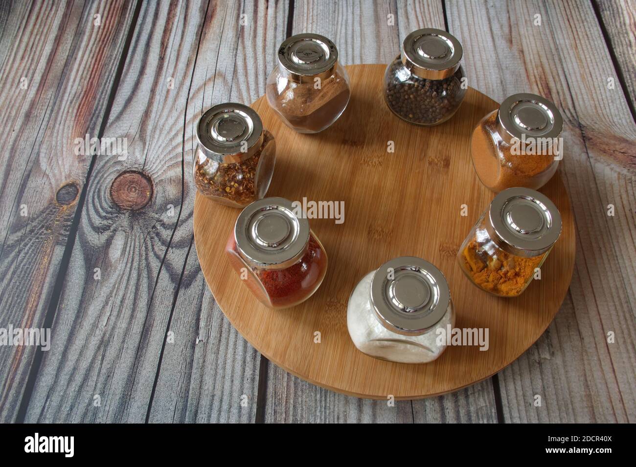 Diverses herbes et épices colorées dans un récipient en verre sur bois arrière-plan Banque D'Images