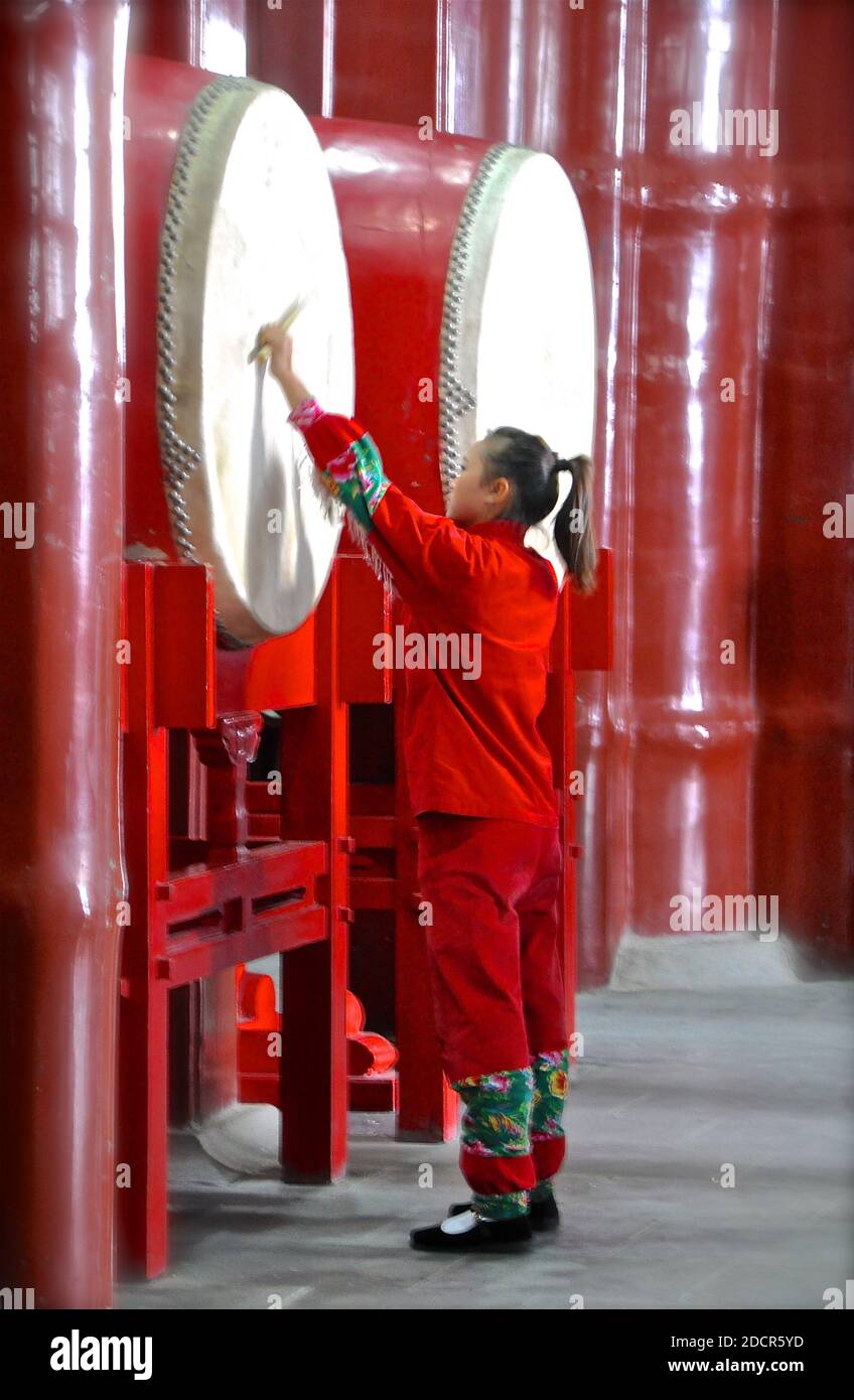 Vue latérale d'une fille chinoise jouant un énorme tambour traditionnel. Banque D'Images