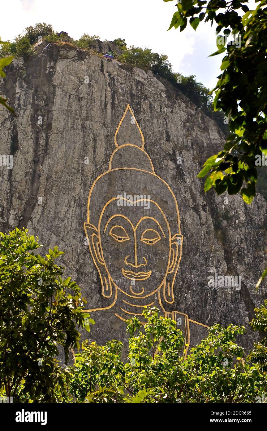 Bouddha de bronze sculptant sur une falaise de roche en Thaïlande. Banque D'Images