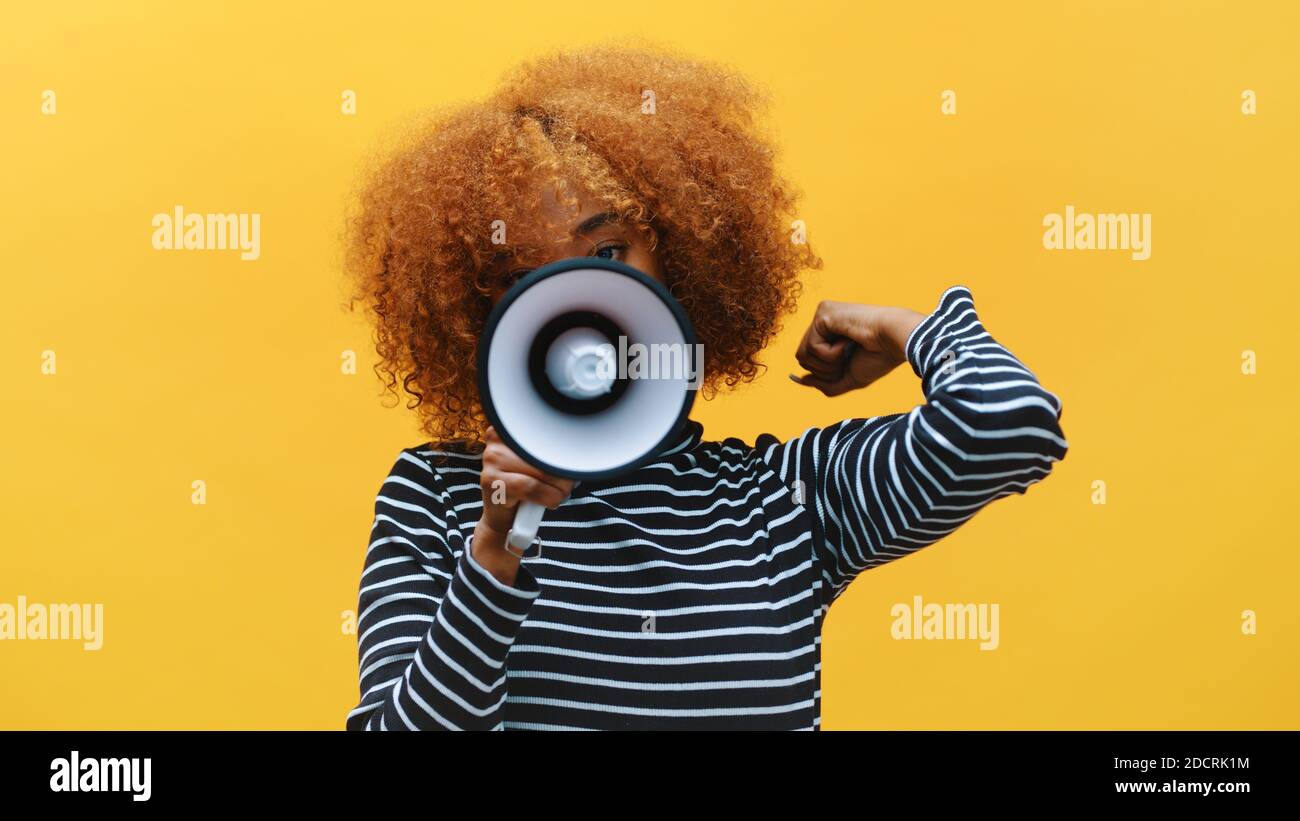 Femme noire afro-américaine aux cheveux bouclés criant dans le haut-parleur. Photo de haute qualité Banque D'Images