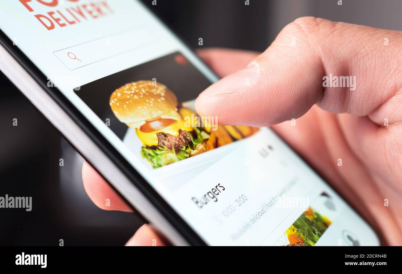 Commande d'application de livraison de nourriture avec téléphone. Service mobile en ligne pour les hamburgers et les pizzas à emporter. Homme affamé lisant le menu du restaurant, le site Web et les commentaires. Banque D'Images