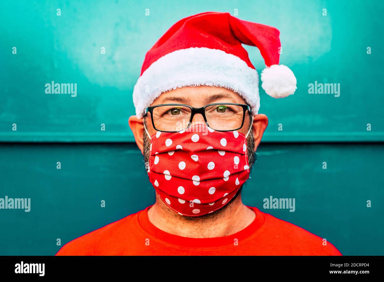 Portrait d'un homme de race blanche adulte portant un masque de protection rouge pour coronavirus vocid-19 et chapeau de chrismtas du père noël - concept de personnes seules pendant ho Banque D'Images