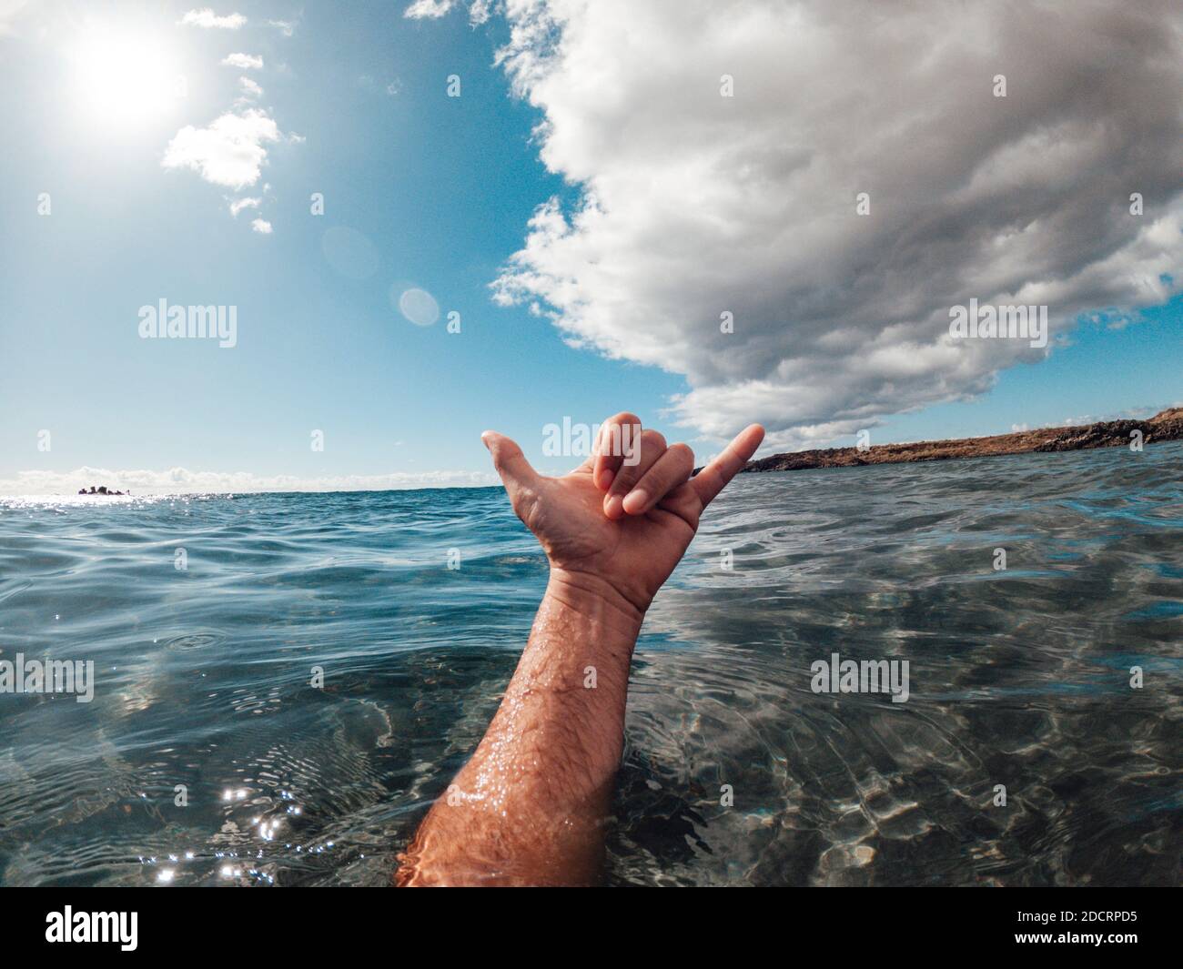 Homme mains dans le surf signe hallo hors du bleu l'eau de l'océan avec la côte et le ciel agréable en arrière-plan - concept de personnes et vacances d'été Banque D'Images