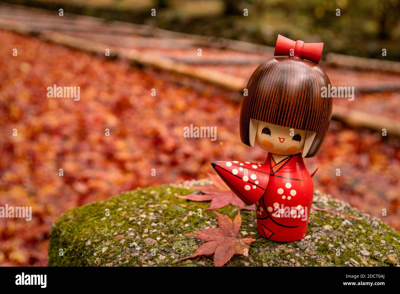 Poupée en bois de kokeshi japonais, en arrière-plan d'automne. Banque D'Images