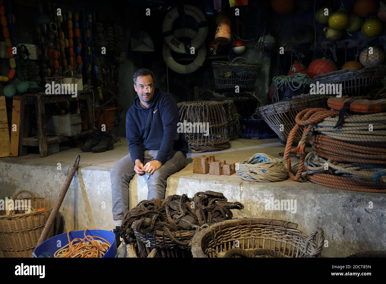 Angleterre / Cornouailles / Saint Ives / l'artiste Sam Bassett posant dans la cave HE sous les studios d'artistes où les pêcheurs fixent des filets sur la plage de Porthmeor. Banque D'Images