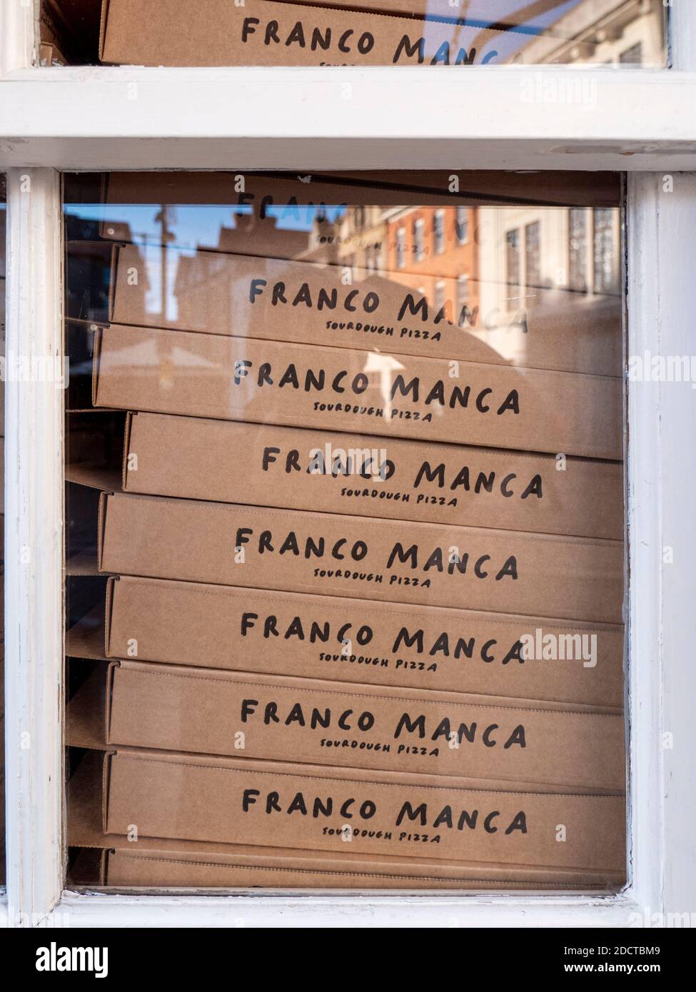 Boîtes à pizza en carton empilées dans une fenêtre d'un Franco Restaurant de pizza Manca Sourdough Banque D'Images