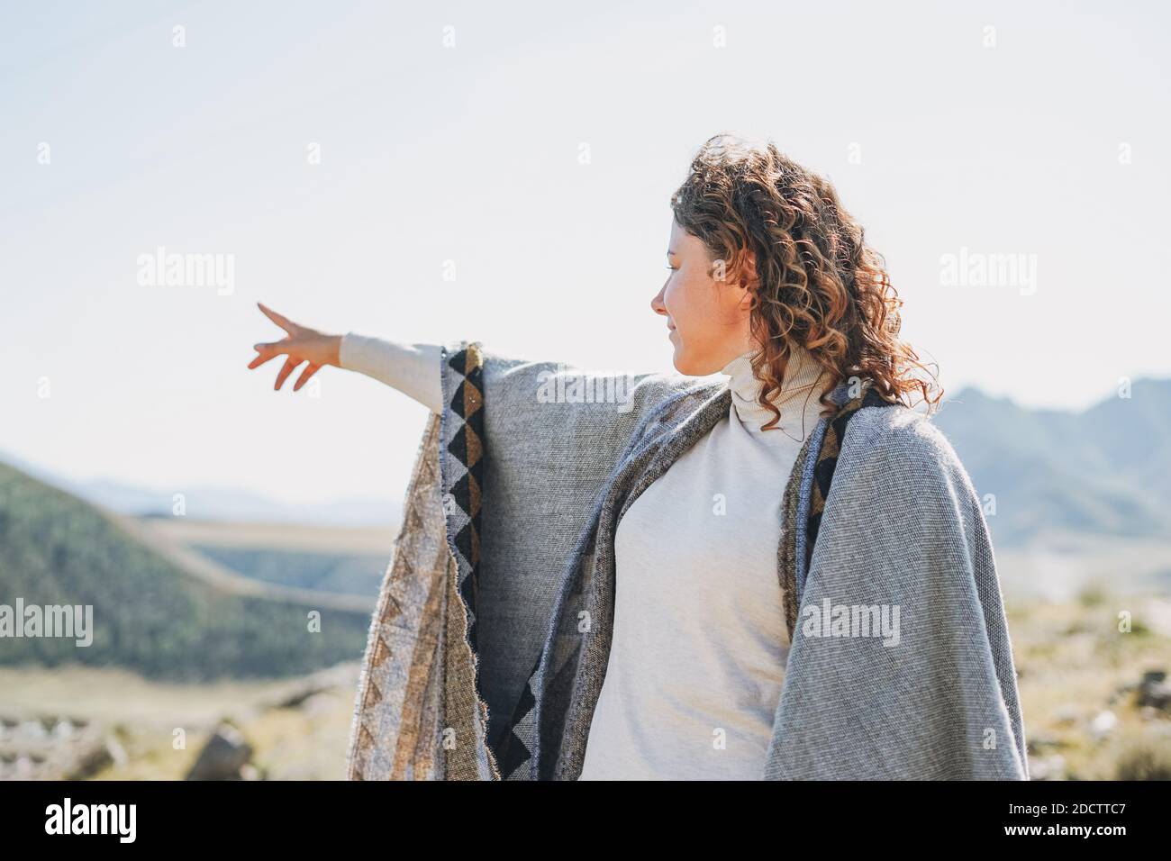 Brunette jeune femme voyageur à poncho de retour sur beau vue sur les montagnes Banque D'Images