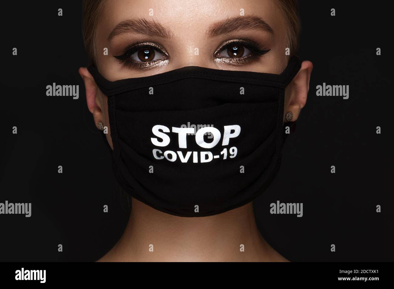 Portrait d'une belle femme dans un masque noir stop covid et maquillage classique. Mode masque pendant la pandémie de covid Banque D'Images