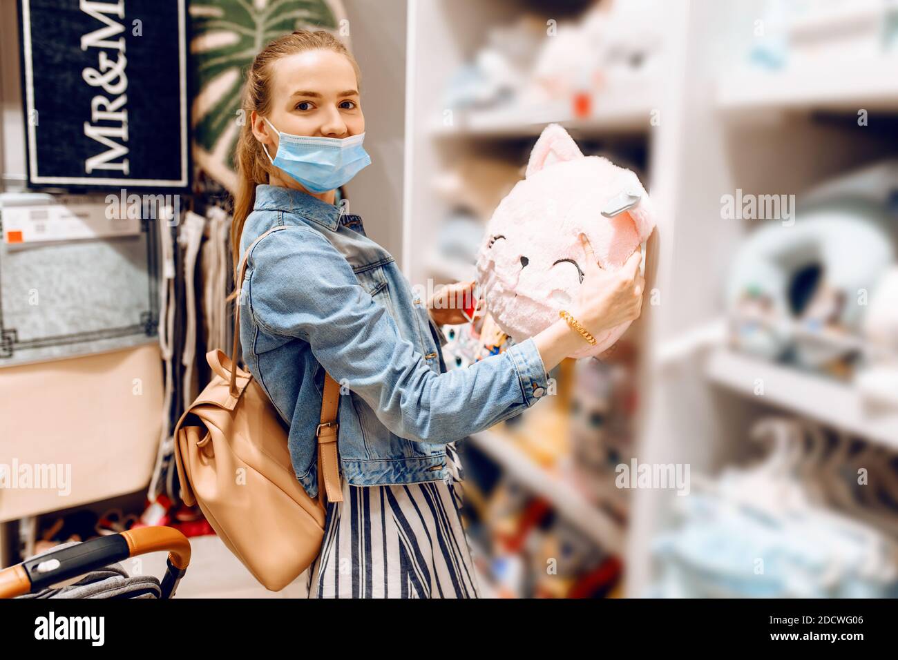 jeune belle femme dans un masque médical protecteur sur son visage, avec un petit enfant dans une poussette, shopping dans un centre commercial. Quarantaine, coronavir Banque D'Images