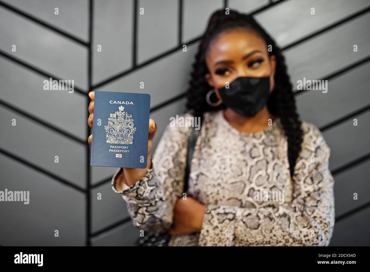 Femme afro-américaine portant un masque noir montrer le passeport du Canada en main. Coronavirus dans le pays américain, fermeture de la frontière et quarantaine, virus outb Banque D'Images