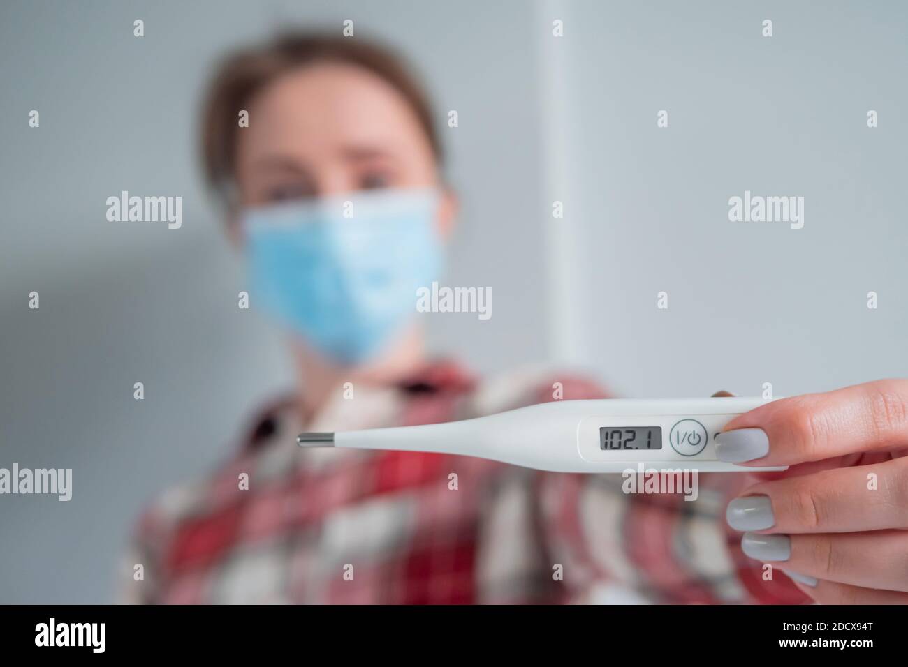 Femme en masque facial montrant un thermomètre médical avec un corps élevé  température Photo Stock - Alamy