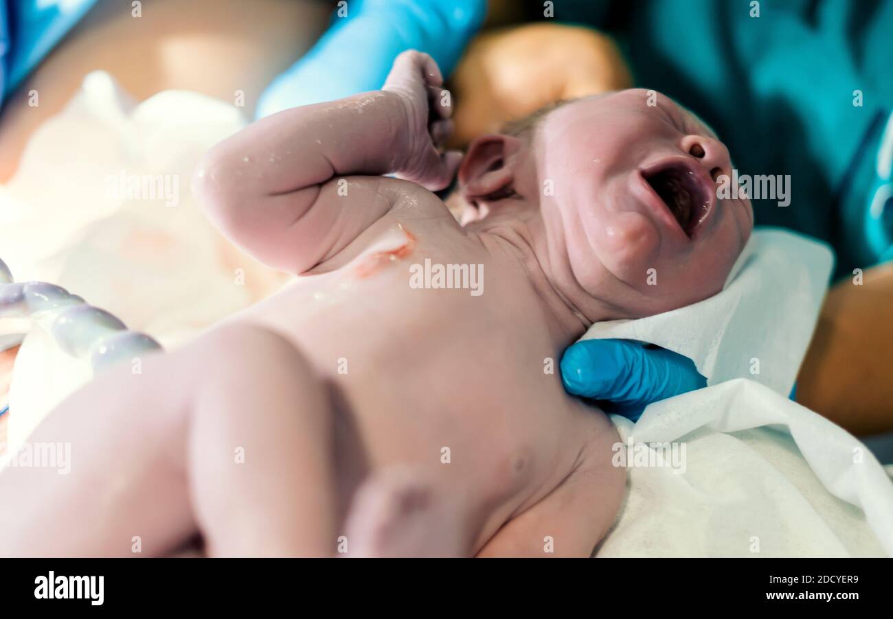 Nouveau-né bébé garçon toujours avec le cordon ombilical le reliant à mère Banque D'Images