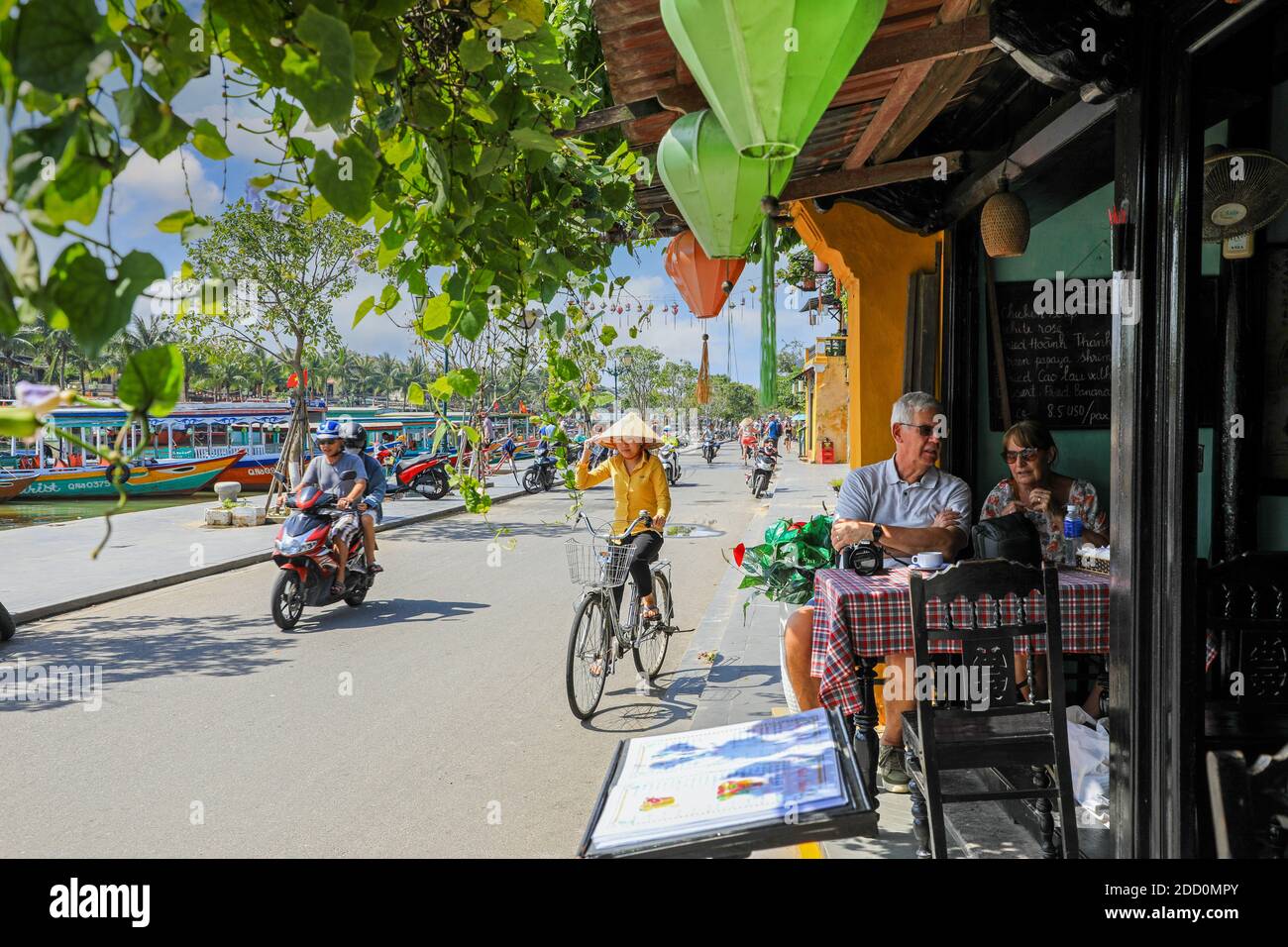 Une femme vietnamienne portant un chapeau conique traditionnel et faisant du vélo sur Bach Dang Street, Hoi an, Vietnam, Asie Banque D'Images