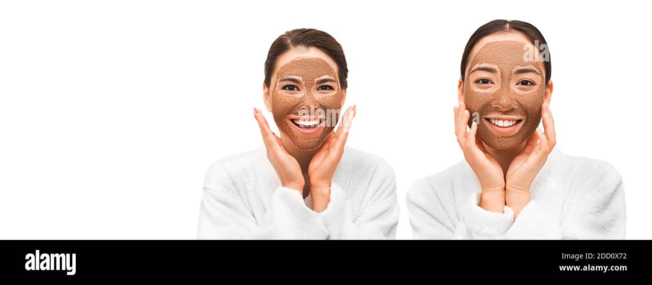 Masque de boue. Deux belles femmes asiatiques avec des masques faciaux sur leur visage, souriant. Isolé sur blanc Banque D'Images