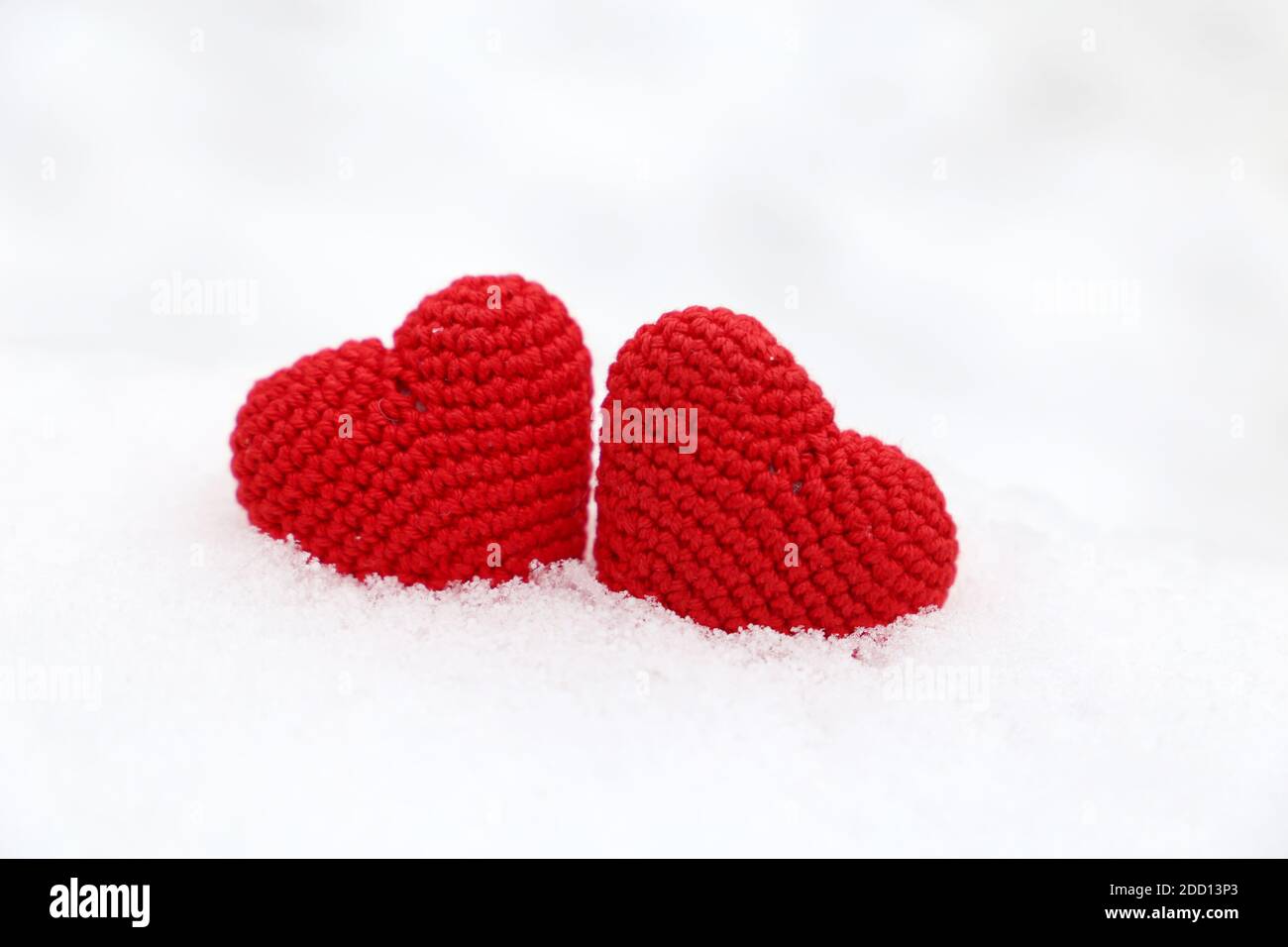 Coeurs d'amour, deux tricotés rouges symboles de passion dans la dérive de neige. Fond pour la carte de Saint-Valentin Banque D'Images