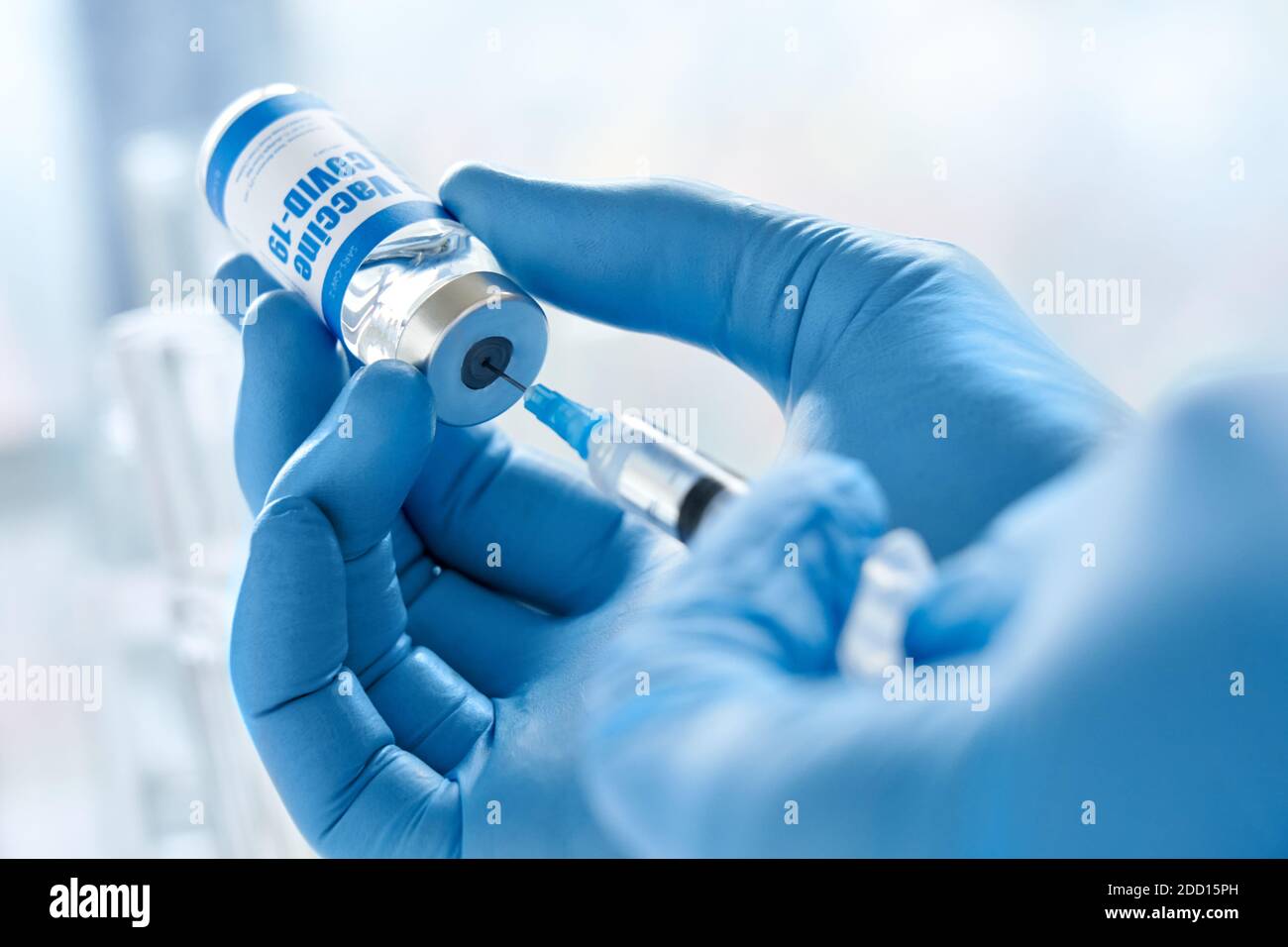 La main d'un médecin porte un gant tenant une seringue prenant le vaccin Covid 19 du flacon. Banque D'Images