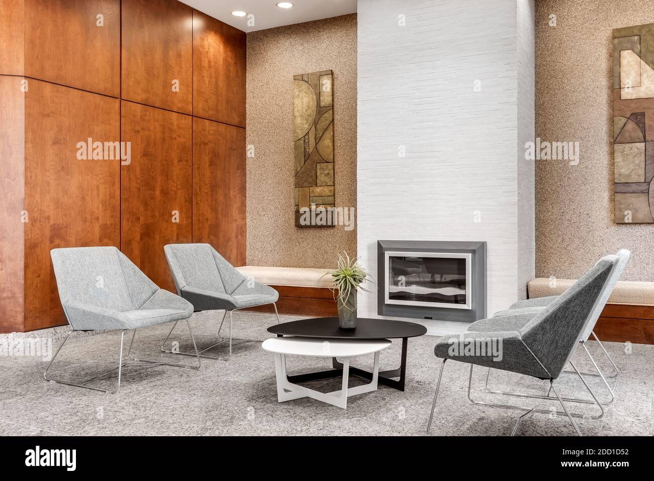 Un salon lumineux et moderne avec une cheminée en pierre derrière des chaises et une table. Banque D'Images